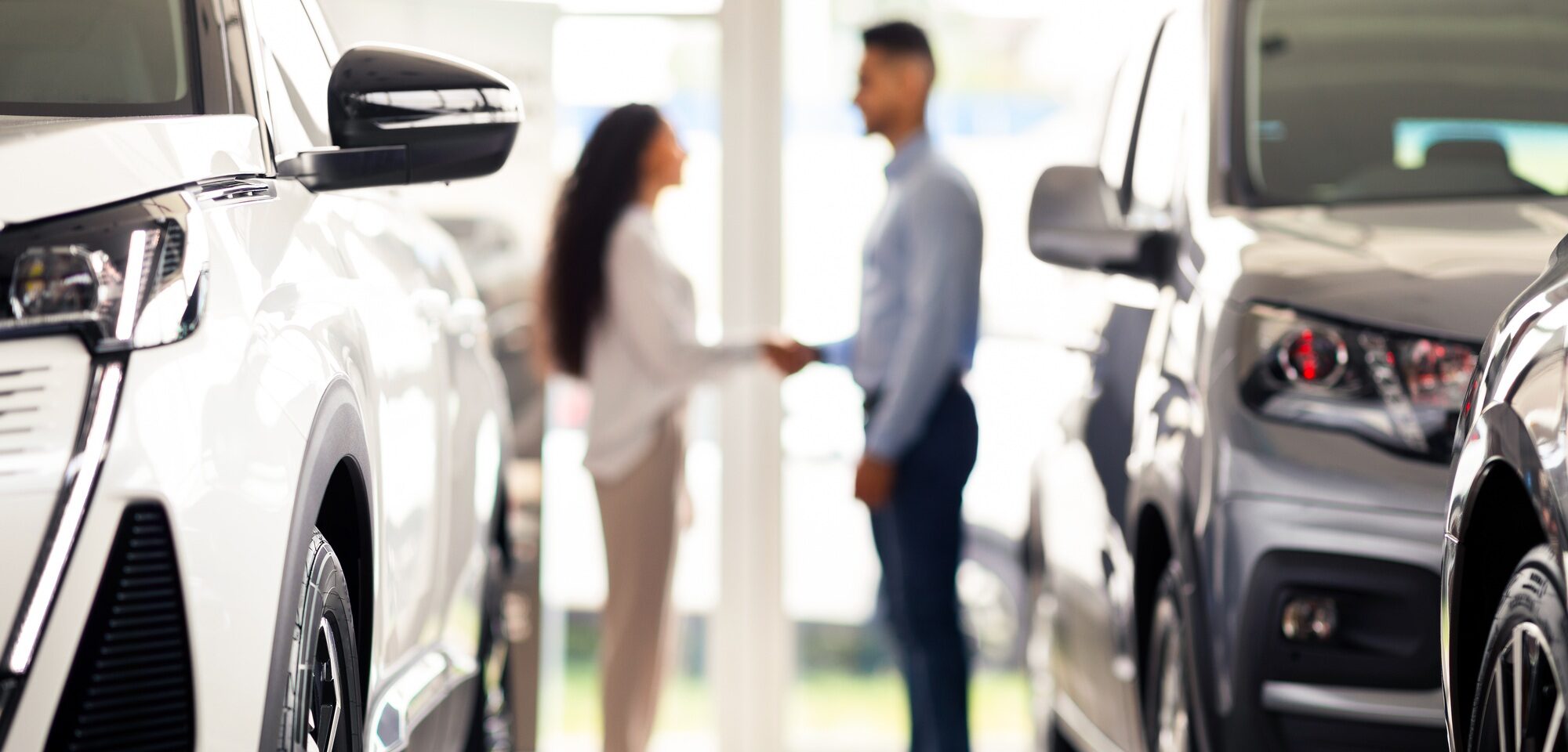 Unrecognizable man and woman shaking hands at auto showroom